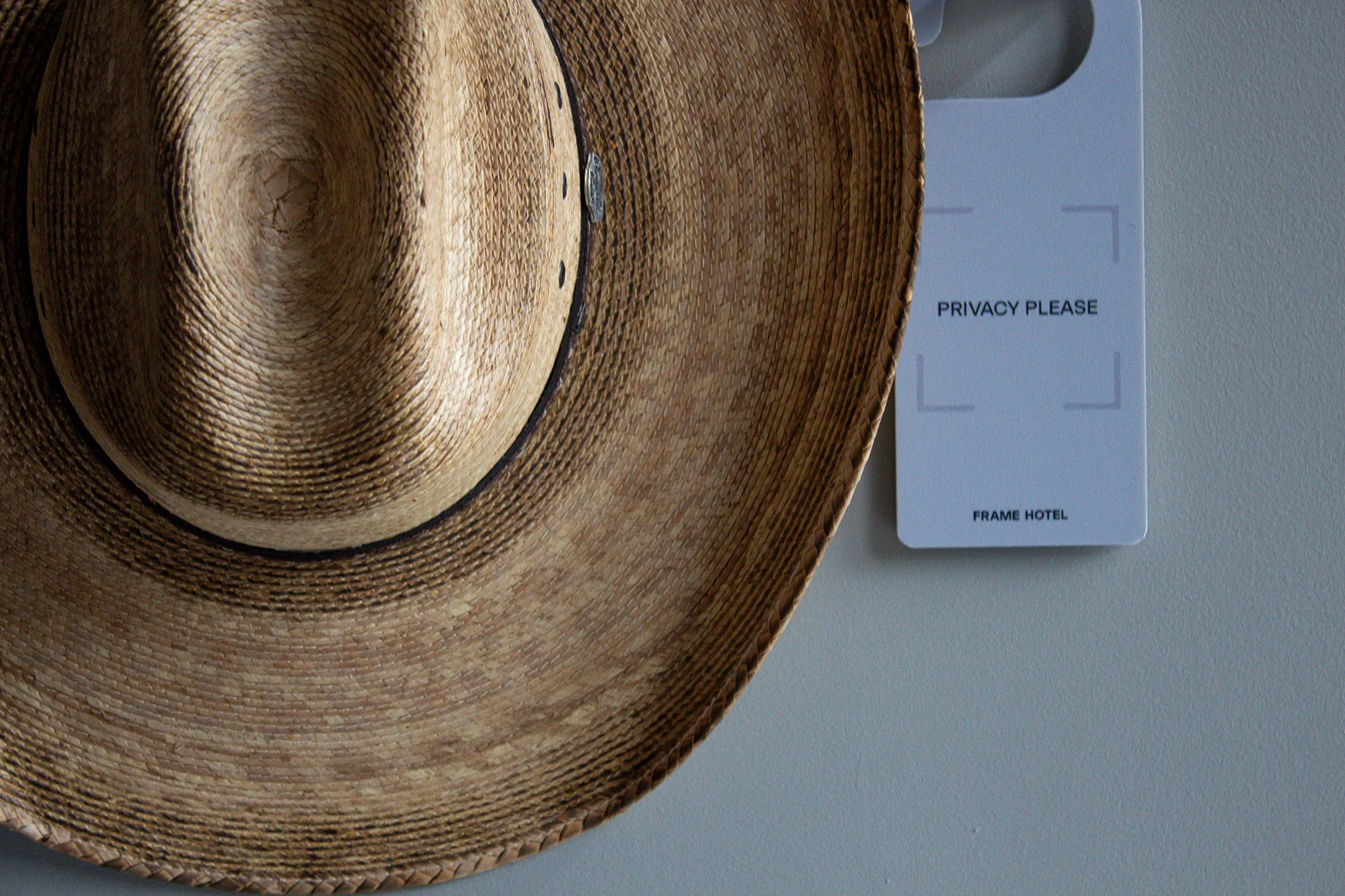 Frame welcome vignette with a guest letter, straw hat, and privacy card laid across crisp bedding